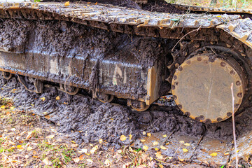 Closeup of a track caterpillar crampon wheel on a truck covered in mud, muddy terrain at workplace...