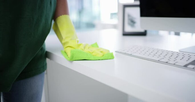 Person, cleaning office and hands as janitor, disinfecting and bacteria with safety gloves, worker and workplace. Service, hygiene and cleaner for sanitizing desk, cloth and professional cleaner