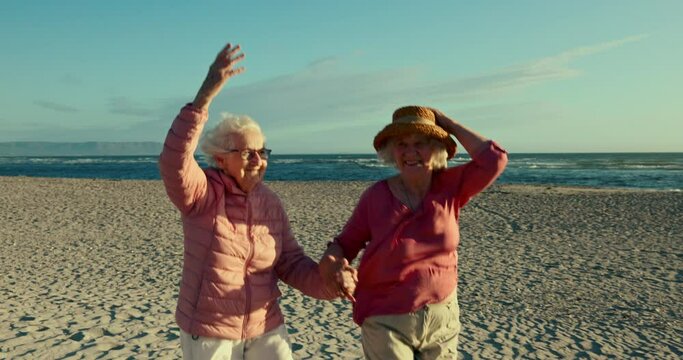 Beach, friends or holding hands with senior women, fun or retirement with adventure, sand or peace. Happiness, outdoor or elderly people with holiday, freedom or ocean with wellness, wind or skipping