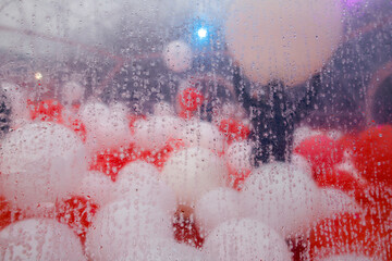 Colorful blue and white balloons inside a large egloo, seen through a wet plastic surface.