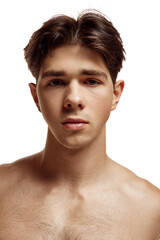 Close up portrait of young attractive brunette man with bare shoulder looking at camera against white studio background. Concept of natural beauty, body care, male health, masculinity,