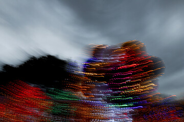 Christmas lights photographed with long exposure and camera movement, trail effect, gray sky.