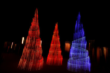 Illuminated Christmas trees, photographed with long exposure and camera movement, trail effect,...