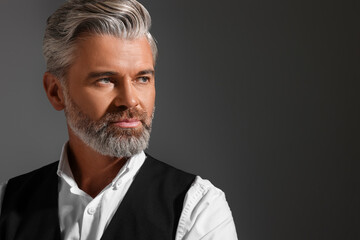 Portrait of confident man with beautiful hairstyle on dark background. Space for text