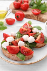 Delicious Caprese sandwiches with mozzarella, tomatoes, basil and pesto sauce on white wooden table, closeup