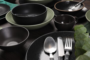 Stylish table setting with cutlery and eucalyptus branch on dark wooden background, closeup