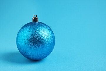 One Christmas ball on light blue background. Space for text