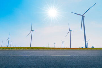 long roads and electric wind turbine farms behind. blue sky clean and renewable energy....