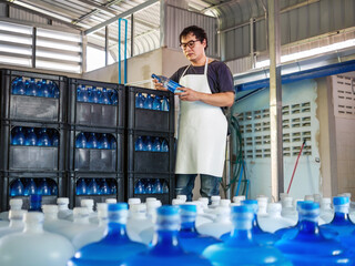 Young Asian man worker wear glasses.working in checking bottled drinking water in drink water...