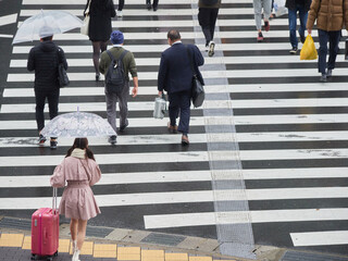 冬の雨の日に都市の交差点の横断歩道を渡る人々の姿、