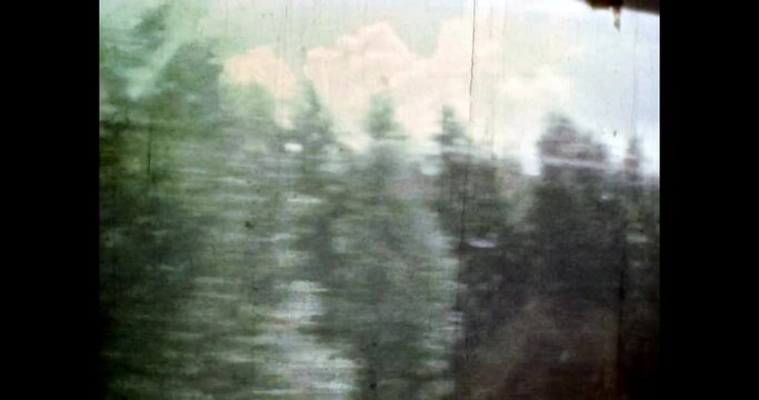 Spruce forest in motion on blue cloudy sky background. Green forest nature in summer moving. Natural pine landscape. Travel in scenic woods. 4k vintage footage of overscan archival film. 1980s archive
