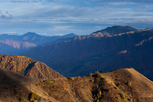 mountain ranges at sunset, an ancient tower at the top of the pass