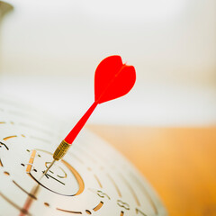 Darts with dartboard, sunset sky background hitting target. Achieve Goals - Success.