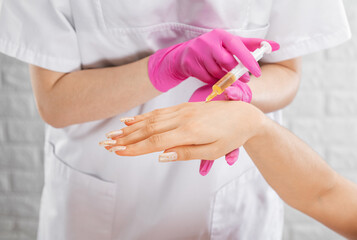 The beautician makes anti-aging injections on the woman's hand. Women's cosmetology skin care.