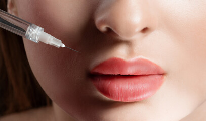 Cosmetologist does injections for lips augmentation of a beautiful woman. Women's cosmetology in...