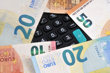 Clavier de calculatrice entouré de billets de banque en euros en gros plan