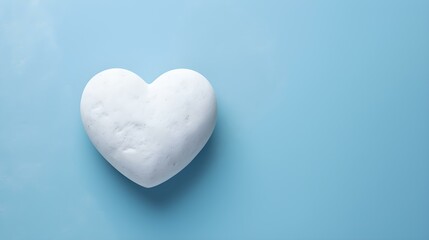 Fototapeta premium Top View of a White Stone Heart on a blue Background. Romantic Template with Copy Space