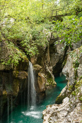 Landscape of Slovenia. A small waterfall flows into the turquoise waters of the Soča River at the bottom of a narrow canyon