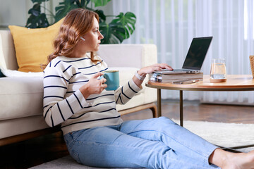 Young woman using laptop while sitting behind table at home