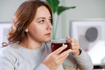 Young woman drinking her winter tea at home