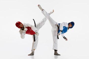 Athletic, strong young men, taekwondo athletes in motion, fighting, training isolated over white...