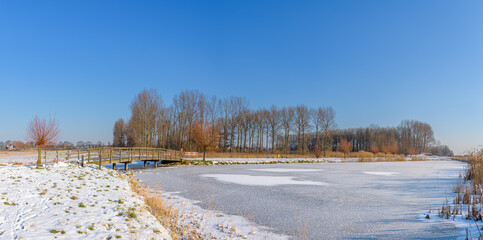 Winter polder landscape. Snow on the grass and a frozen ditch