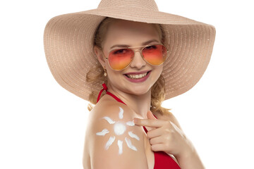 Beautiful smiling blond woman in red bra with cosmetic product in smile shape on her shoulder on white background.