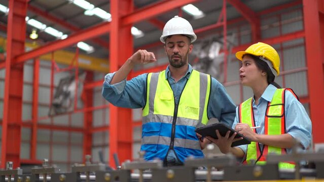 mechanical engineer inspecting machines and robotic system in manufacturing factory. 