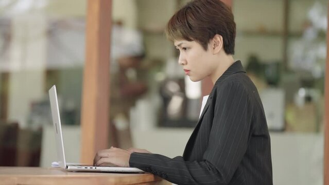 The image portrays a businesswoman working diligently in her office, focused on her laptop amidst a professional setting