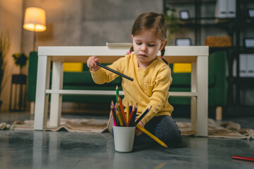 Toddler girl caucasian child play with crayons at home