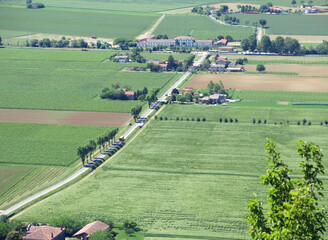 road that crosses the plain seen from above and the cultivated fields in summer