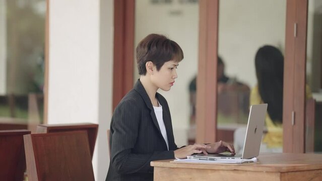 The image portrays a businesswoman working diligently in her office, focused on her laptop amidst a professional setting