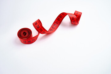 Red measuring tape on a red background. Tool for measuring length and volume. Tape for measuring in...
