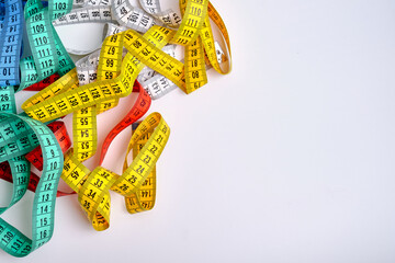 Multi-colored measuring tapes on a light background. Tool for measuring length and volume. Tape for...