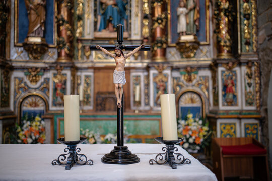 Crucifix with the statue of Jesus crucified next to two candles on the altar of the Church of the Nativity of Durro, in the Bo? Valley, Lleida, Catalonia, Spain.