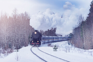 Retro christmas steam train moves through the forest. - 696904441