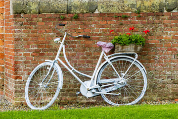 Fototapeta na wymiar Dutch white bike with flower basket filled with red geranium flowers