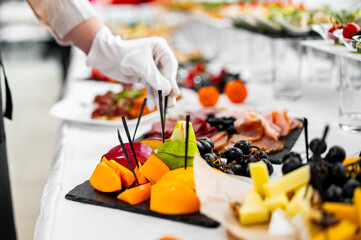 woman hands of a waiter prepare food for a buffet table in a restaurant