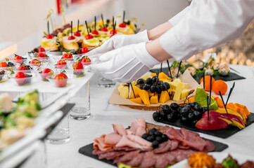 woman hands of a waiter prepare food for a buffet table in a restaurant
