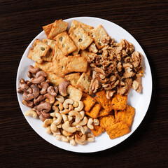 A plate with dry snacks - nuts and crackers. View from above.
