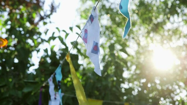 Hand Held Close Up Shot of String of colorful Fabric Flags in the Garden Against the Sun