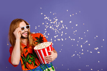 Portrait of good mood positive man touching glasses look at 3d illusion of popcorn flying from screen isolated on purple color background