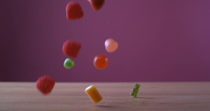Sweet candies falling in super slow motion captured with a high speed camera on pink background, variety assortment of industrial sugary treats