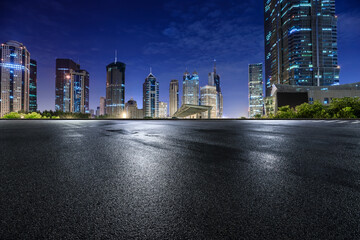 Asphalt road and modern city commercial buildings at night in Shanghai, China.