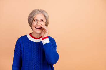 Photo of funny tricky woman with gray hair dressed knit sweater in glasses tell secret look empty...