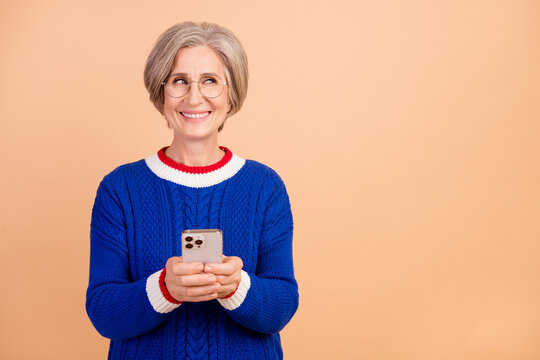 Photo of charming cheerful woman wear stylish clothes thinking buy novelty apple ipone look empty space isolated on beige color background