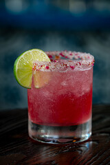 Strawberry Hibiscus Margarita with a slice of Lime and a salt and hibiscus petal rim