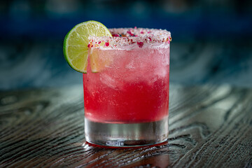 Strawberry Hibiscus Margarita with a slice of Lime and a salt and hibiscus petal rim
