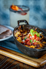 Queso Fundido. Oaxaca and chihuahua cheese on a
skillet with chorizo and pico de gallo, served with blue corn tortillas