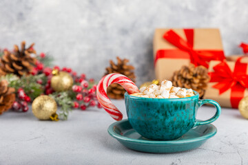 Hot drink with marshmallows and candy cane in blue cup on texture table.Cozy seasonal holidays.Hot...